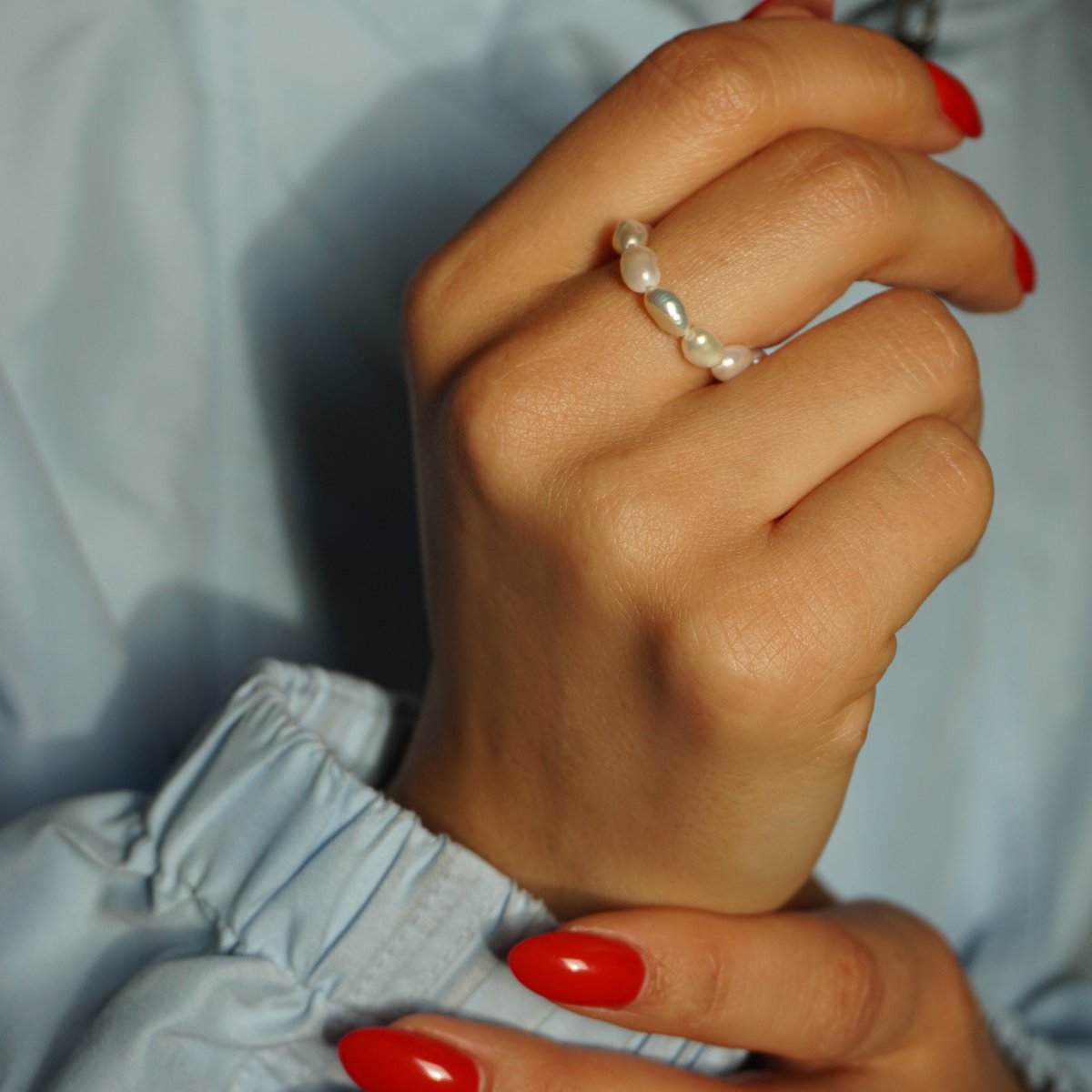 Pearl Gem an der Hand mit roten Fingernägeln