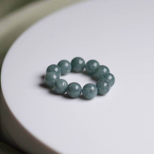 Blue Spruce 6 mm Perlenring elastisch an der Hand vor weißem Hintergrund